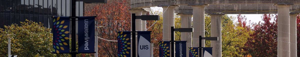 A view of the UIS campus in autumn with several UIS banners hanging.