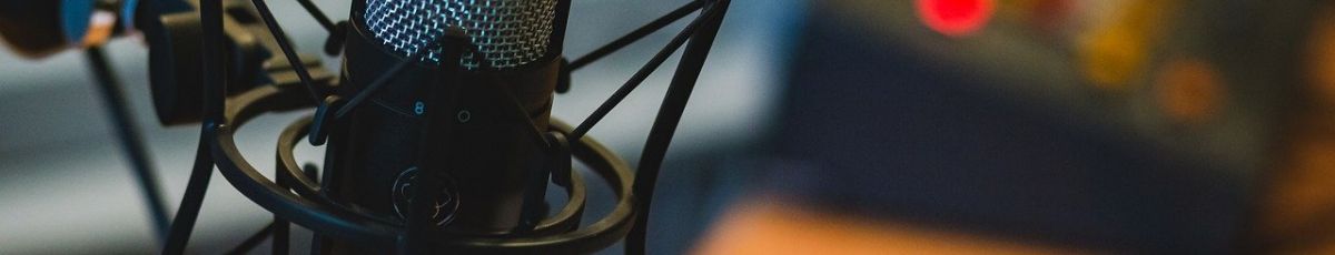 A microphone in focus with desk and recording signal in background