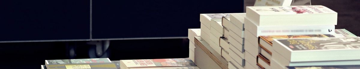 multiple stacks of books for sale in a shop