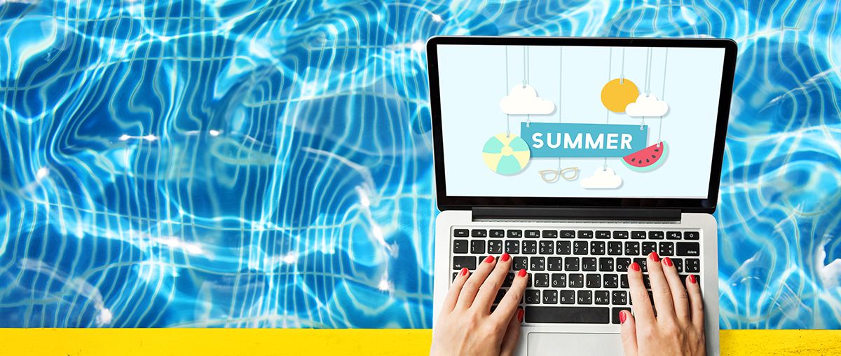 a student sits by the pool on a laptop