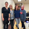 Four FET Quad chairs standing with dean of FDAE in a flex room before a FET meeting.