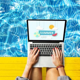 a student sits by the pool on a laptop 