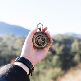 an extended hand holding a compass