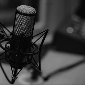 A microphone in focus with desk and recording signal in background