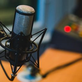 A microphone in focus with desk and recording signal in background