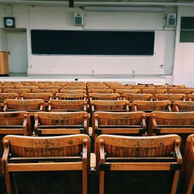 a large empty classroom with wood seats and a view from the back