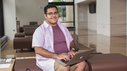 Male student working on laptop in Collins Hall
